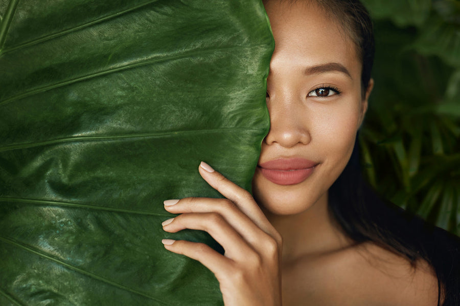 Woman behind a plant used in vegan skincare products.